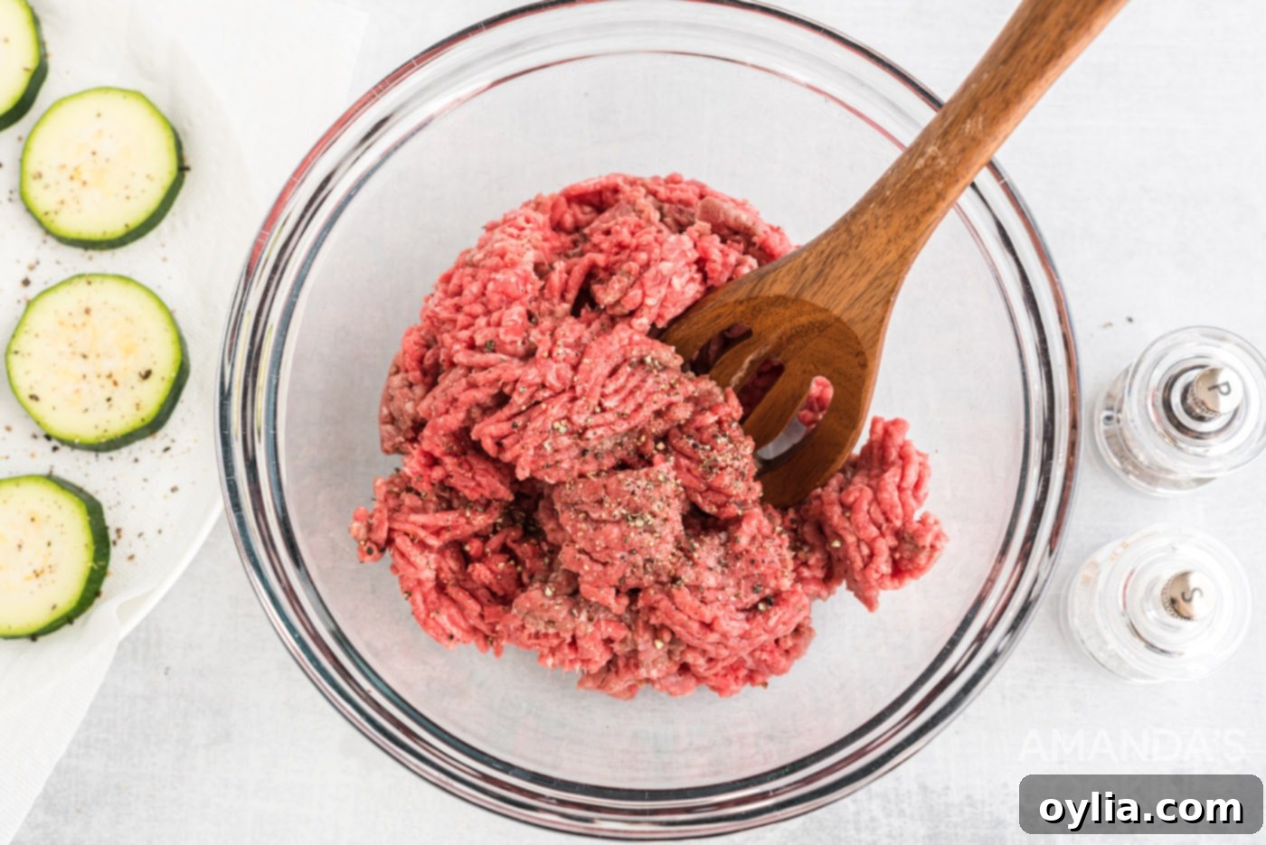 mixing spoon in a bowl of ground beef with salt and pepper