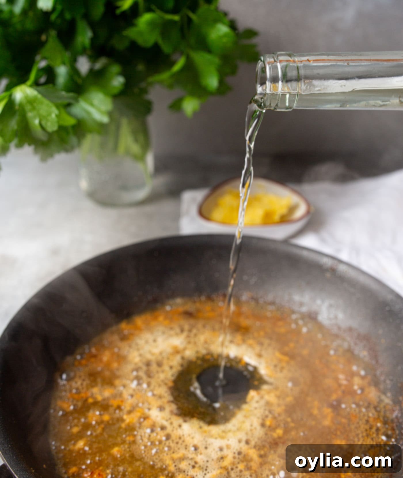 pouring white wine into a hot skillet to deglaze for the sauce