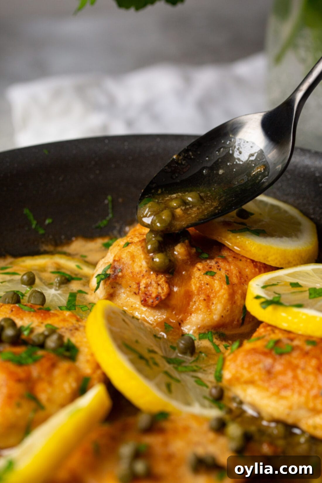 drizzling capers and sauce onto freshly cooked Chicken Piccata