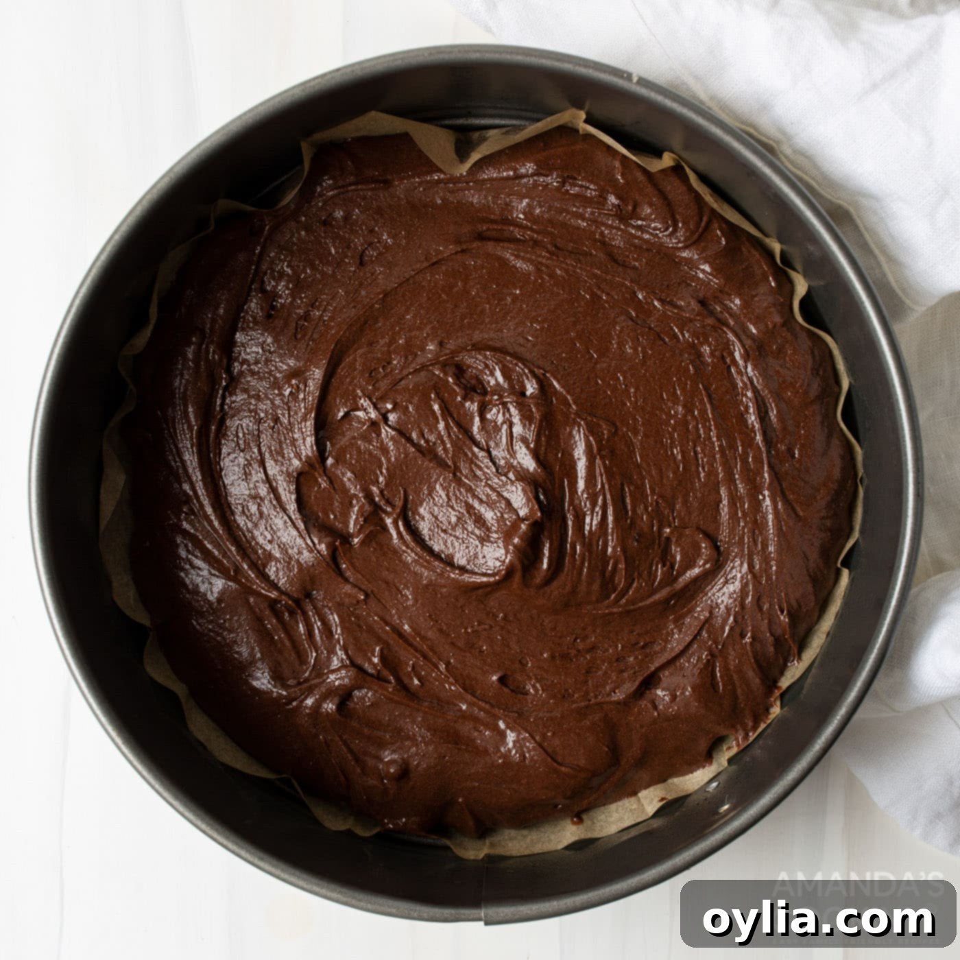 Raw German chocolate cake batter evenly divided into three round baking pans, ready for the oven.