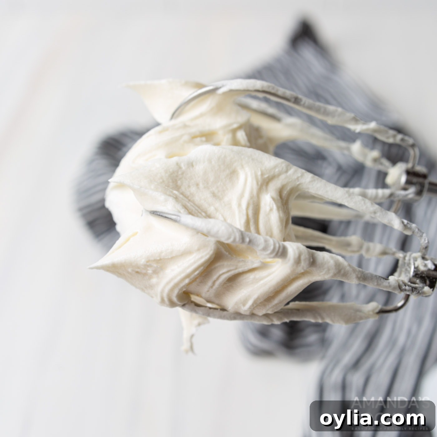 Close-up of fluffy cream cheese frosting on a whisk.