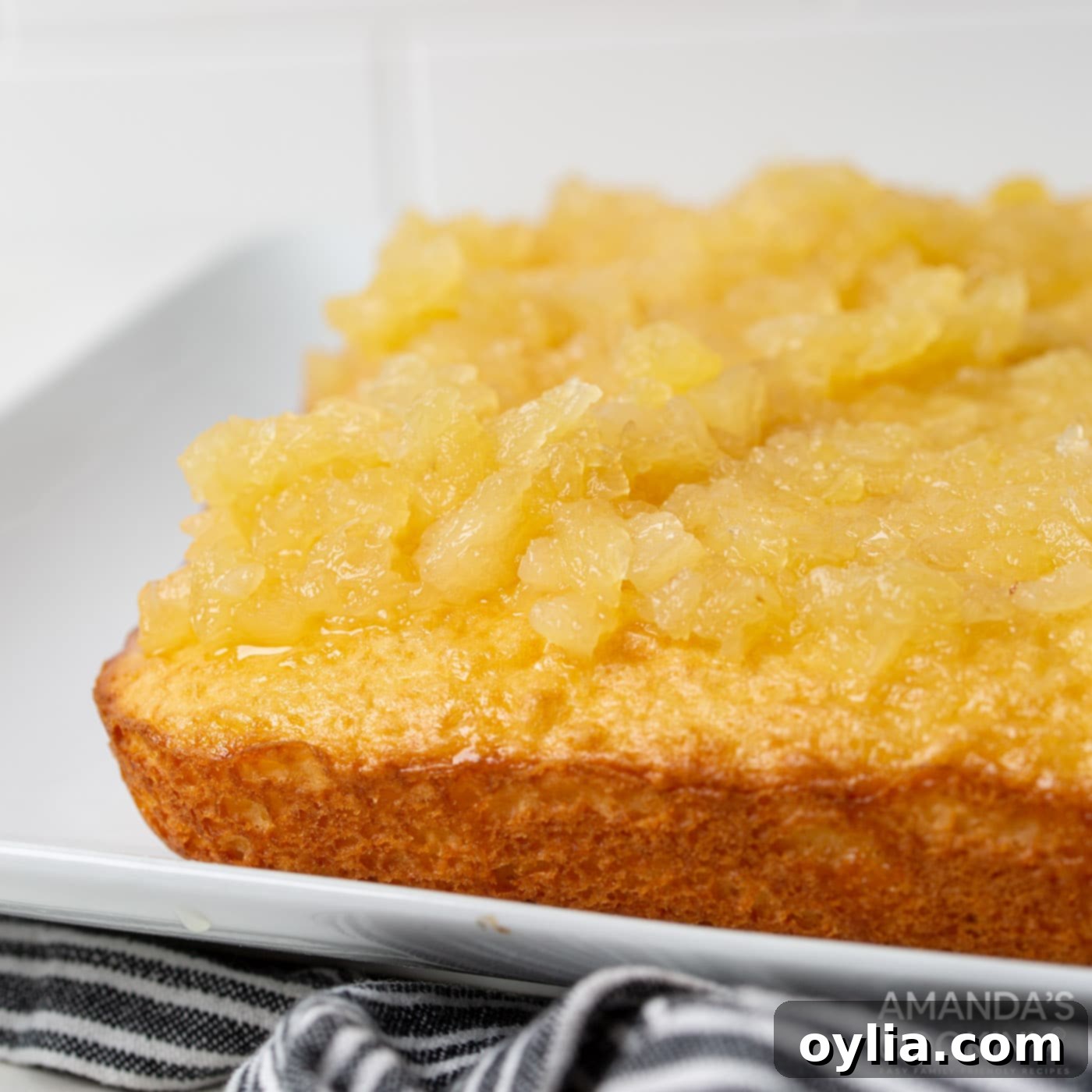 Close-up of pineapple chunks resting on top of the yellow cake after the mixture has been absorbed.