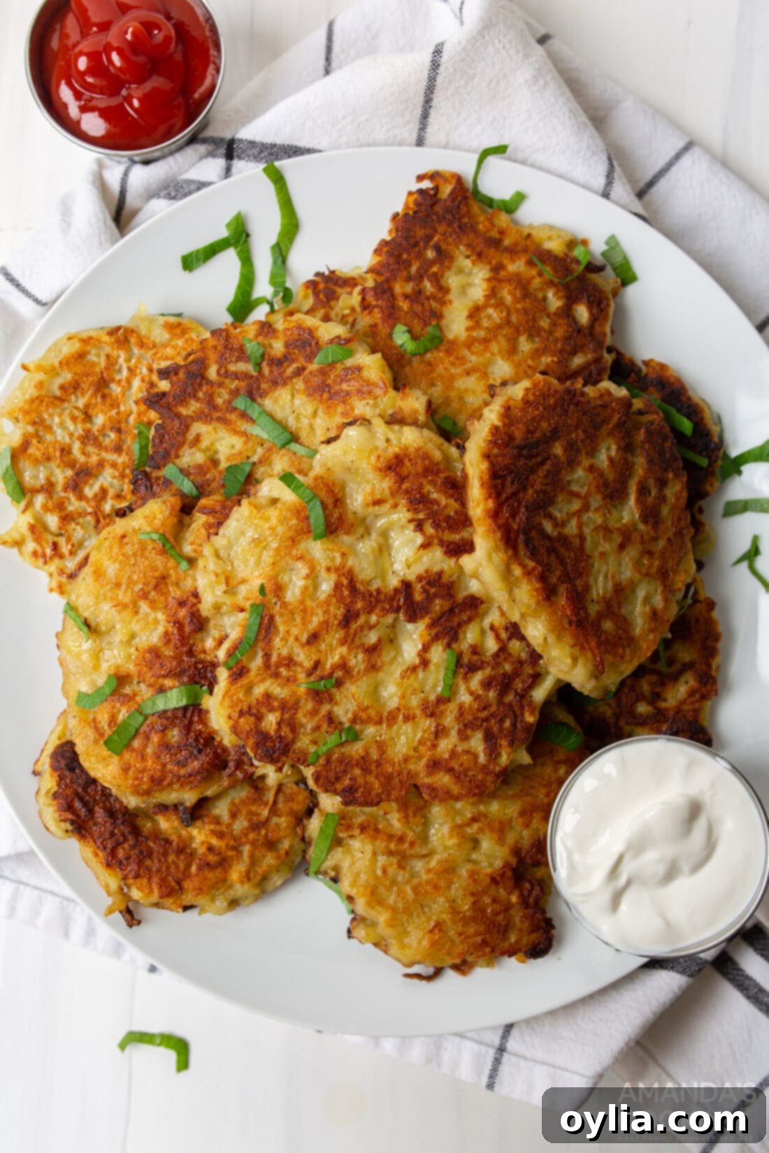 Potato Fritters 3 Plate of freshly fried potato pancakes with a dollop of sour cream and fresh chives.