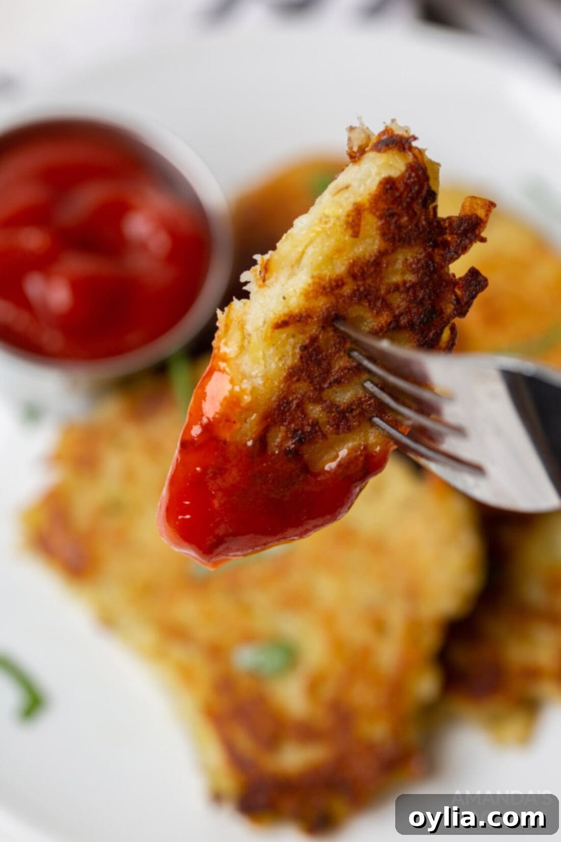 Potato Fritters 8 Crispy potato pancake dipped in ketchup, showing its golden exterior.
