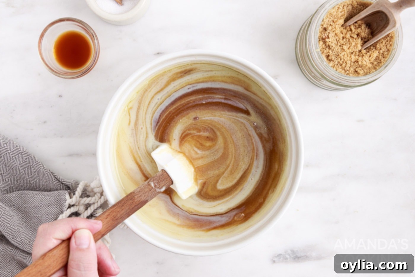 Sweetened condensed milk being whisked into the boiling caramel mixture.
