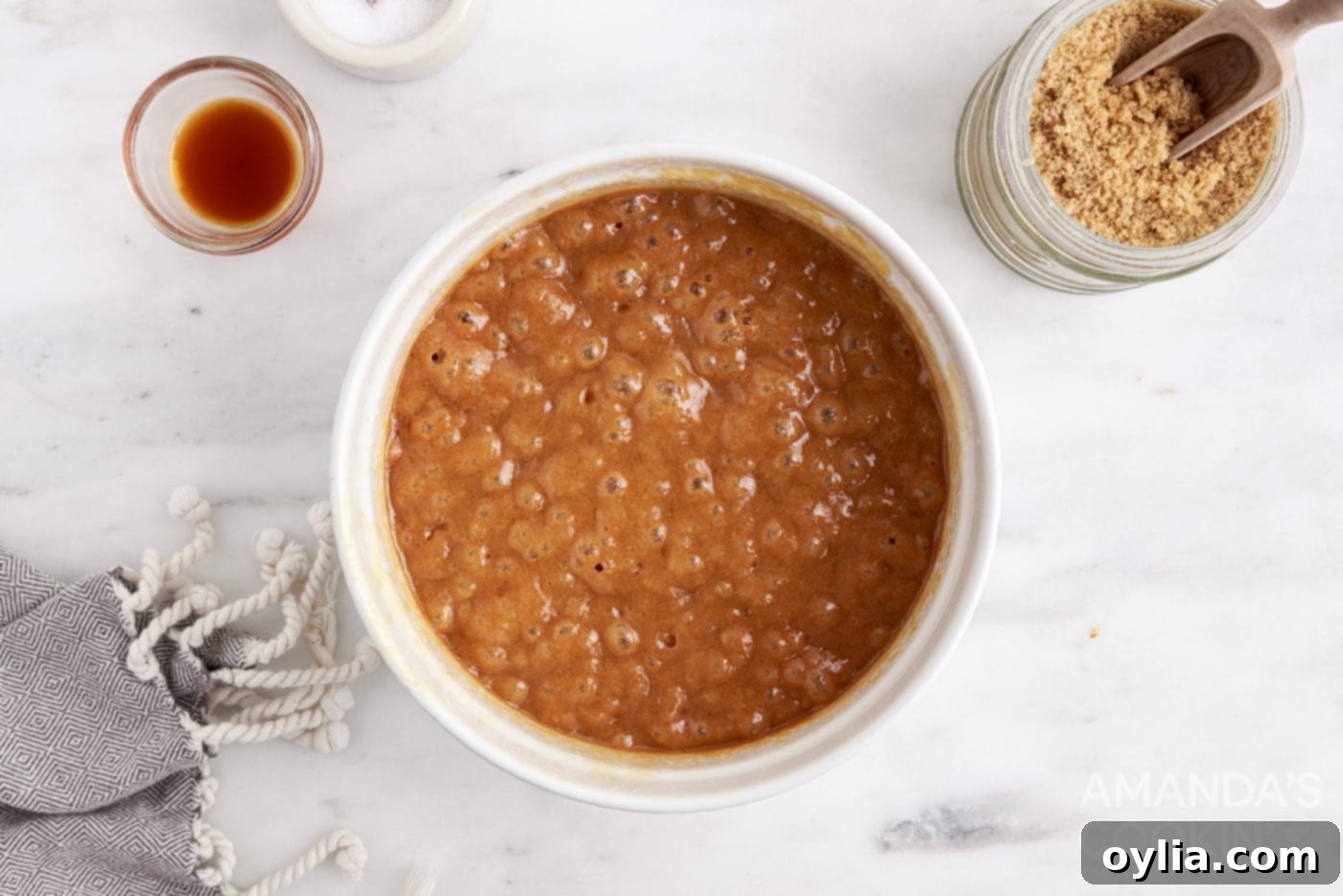 The caramel mixture cooking in a microwave-safe bowl, with a candy thermometer checking the temperature.