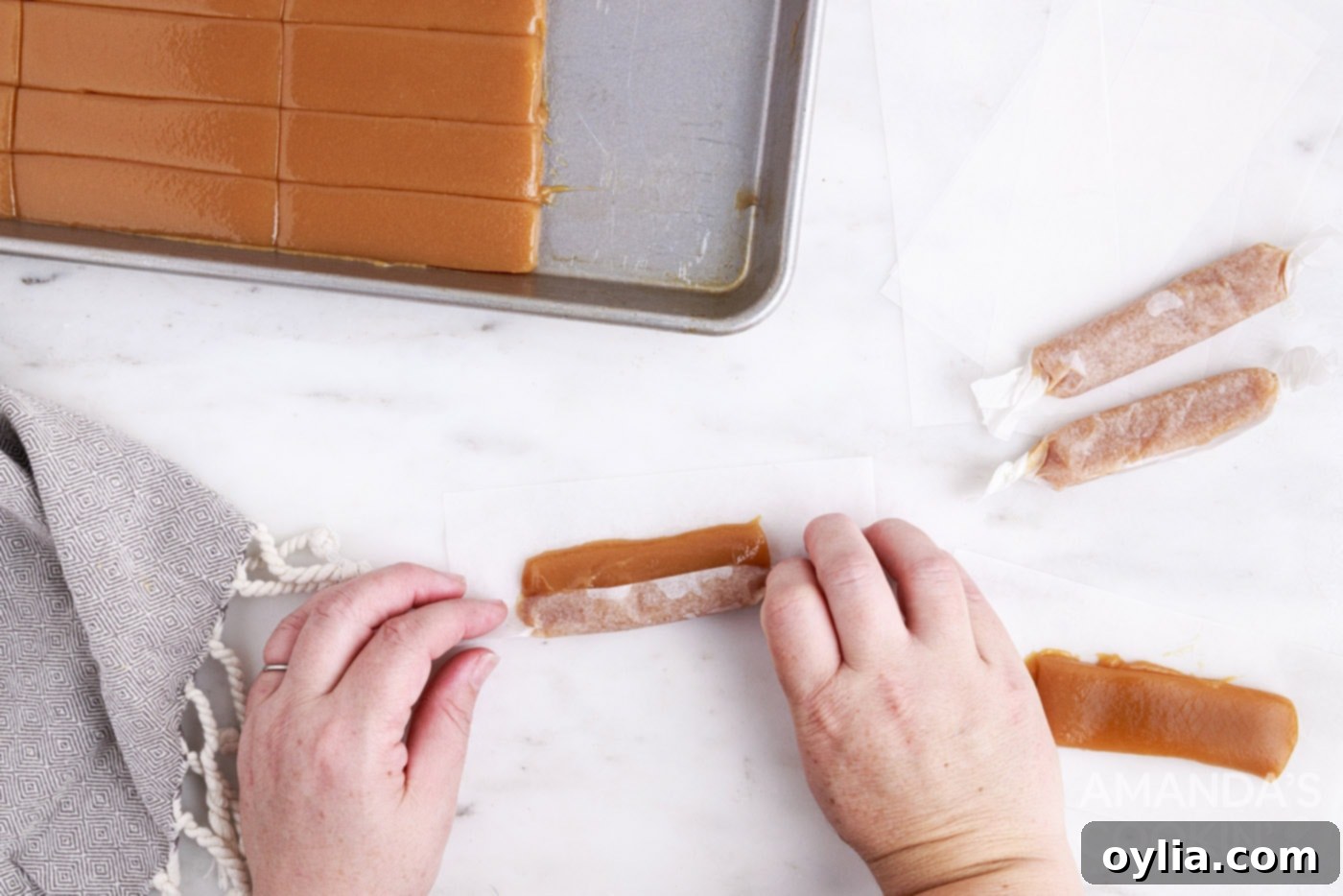 Hand wrapping a microwave caramel in a square of parchment paper.