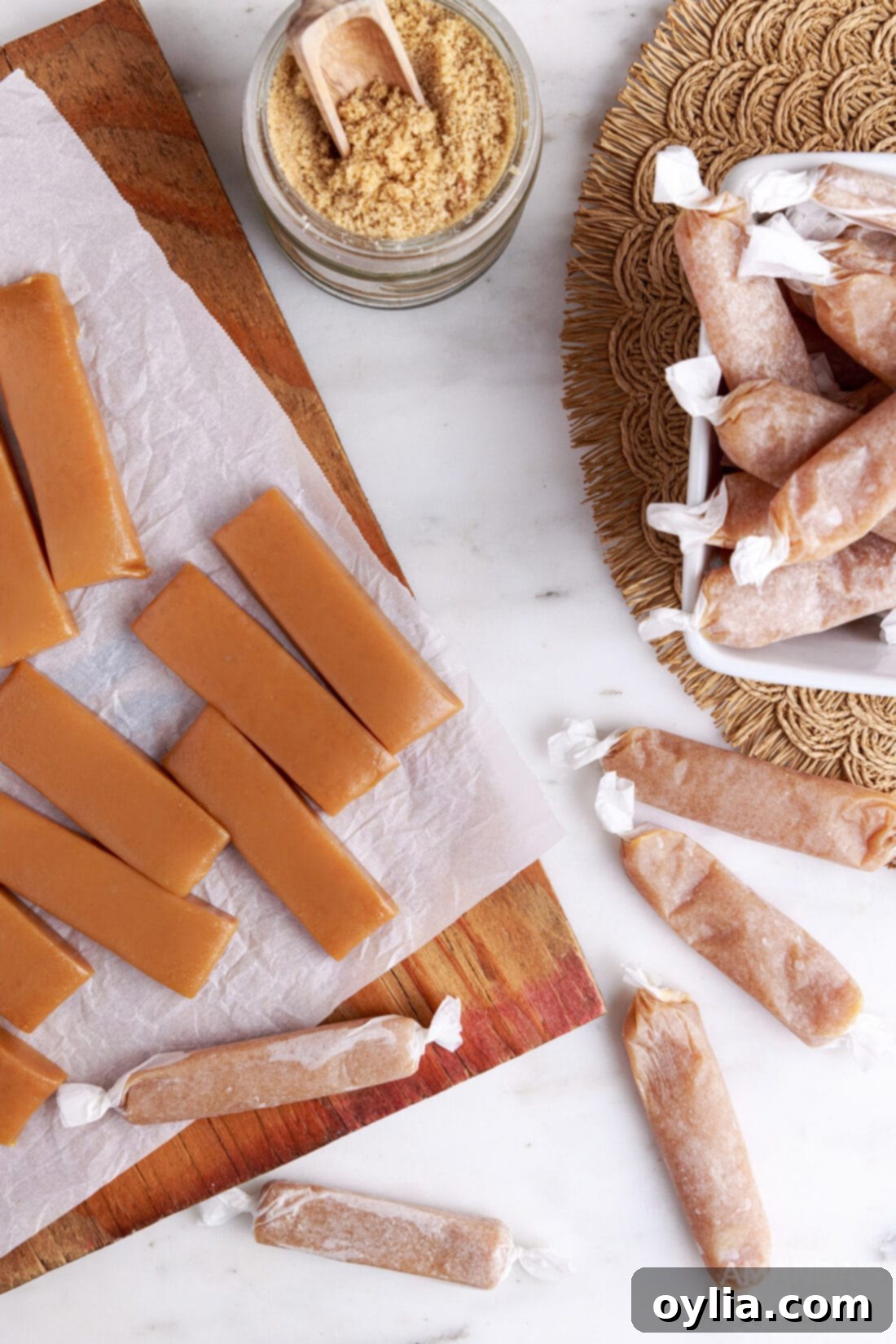 A collection of homemade Microwave Caramels, some wrapped in parchment, others unwrapped, showcasing their golden hue.