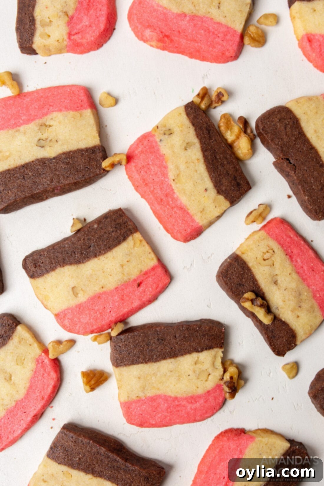 Soft Neapolitan cookies stacked on a white board, showcasing their beautiful pink, white, and brown layers.