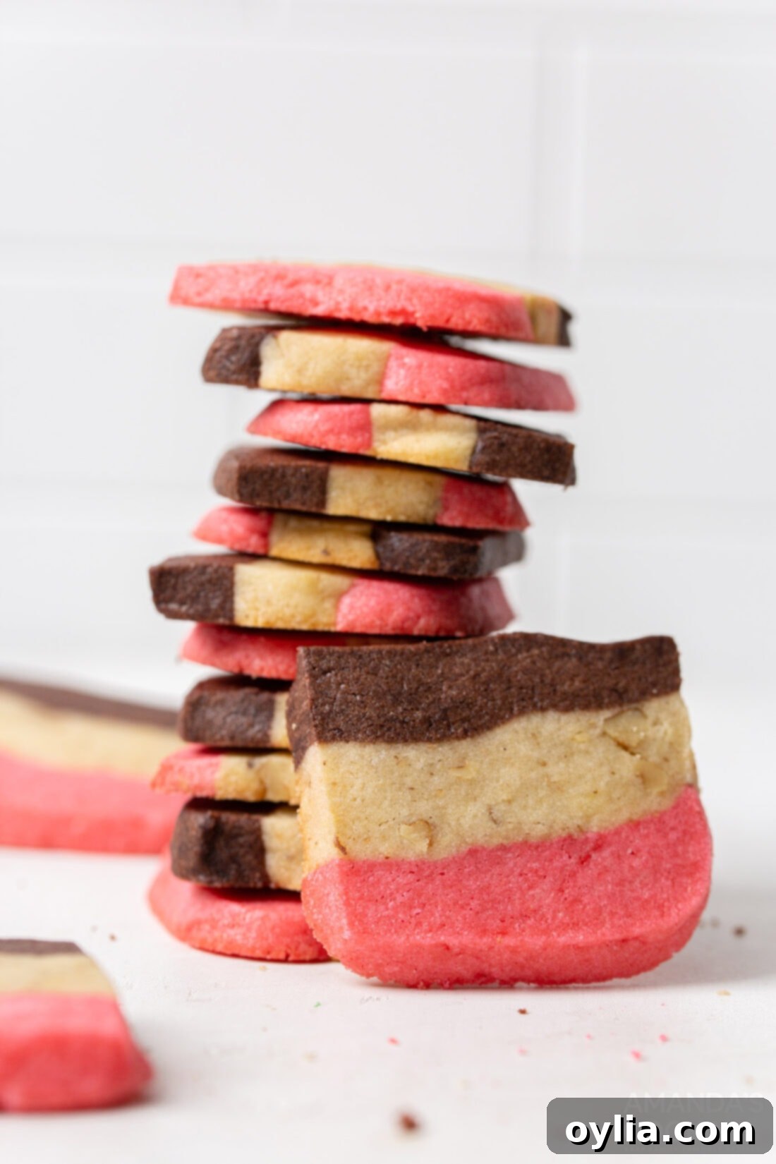 A stack of beautifully layered Neapolitan cookies, showcasing the distinct pink, white, and chocolate sections.