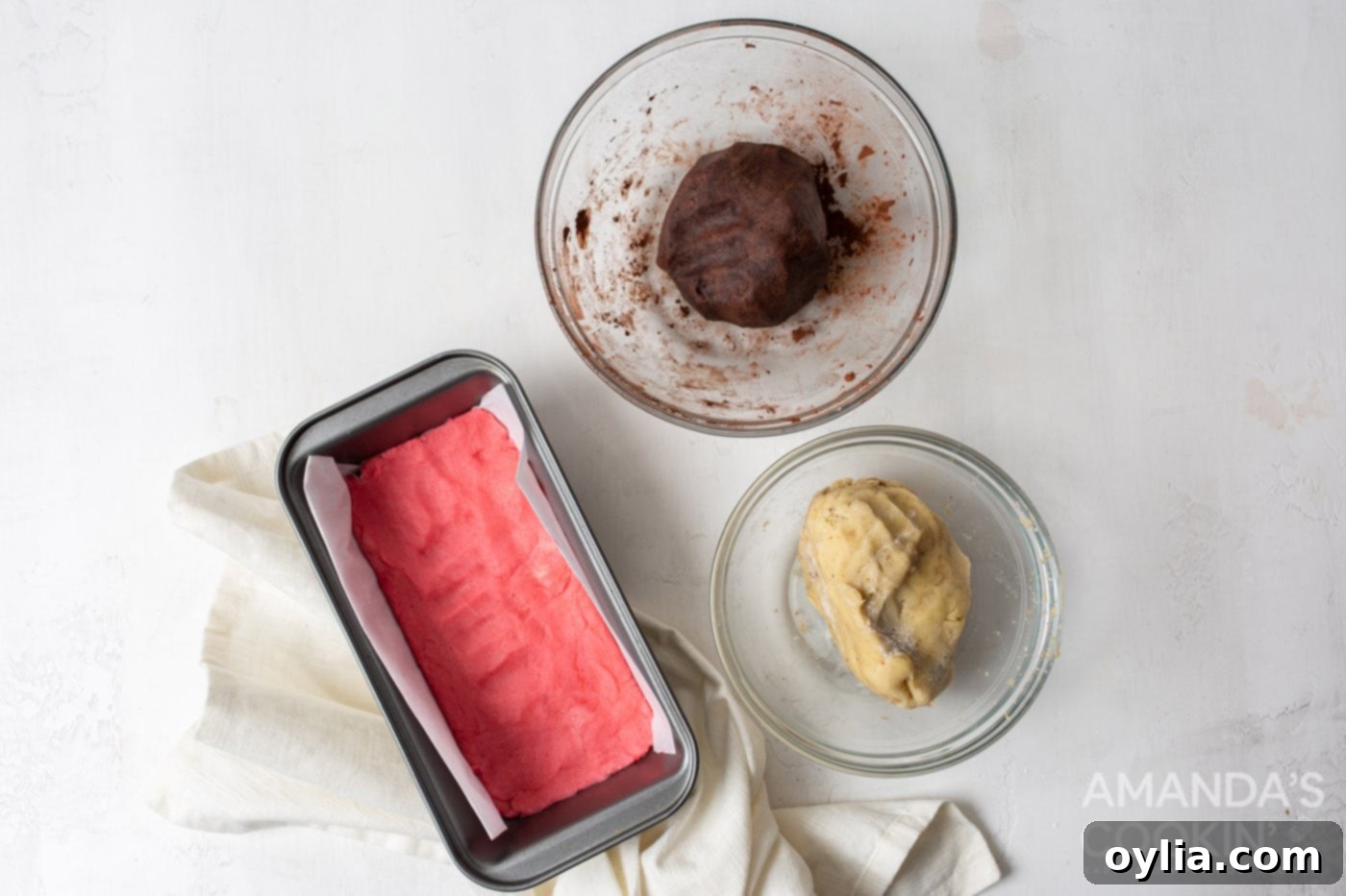 The pink cookie dough layer pressed into a loaf pan lined with parchment paper.