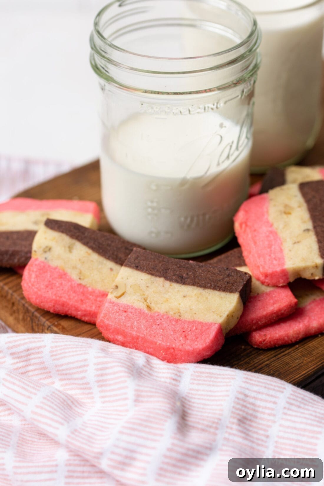 A stack of Neapolitan cookies next to a glass of milk, a perfect pairing.