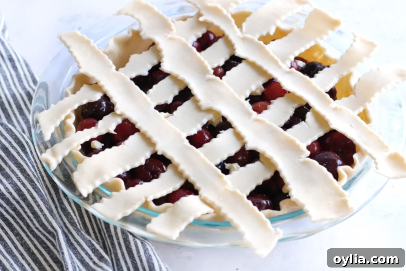 Unbaked cherry pie with a beautifully woven lattice crust on top of the cherry filling.
