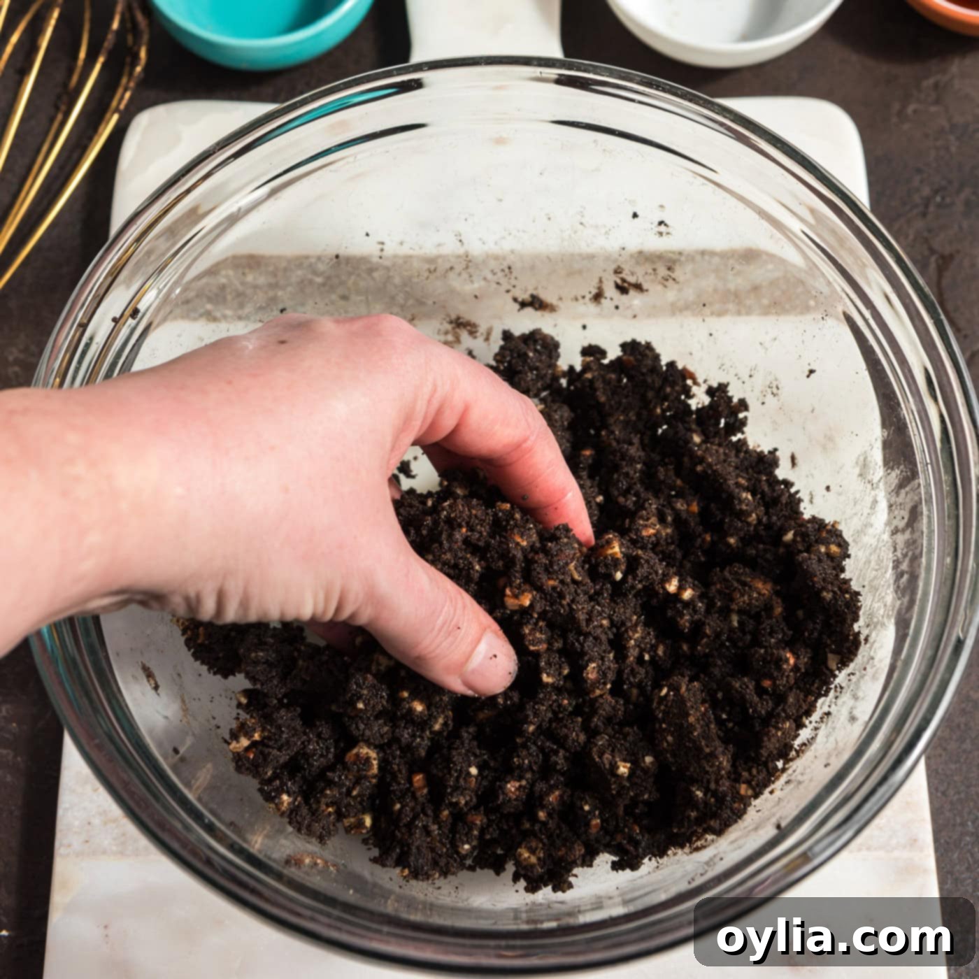 hand fluffing pecan and chocolate graham cracker crust in a bowl