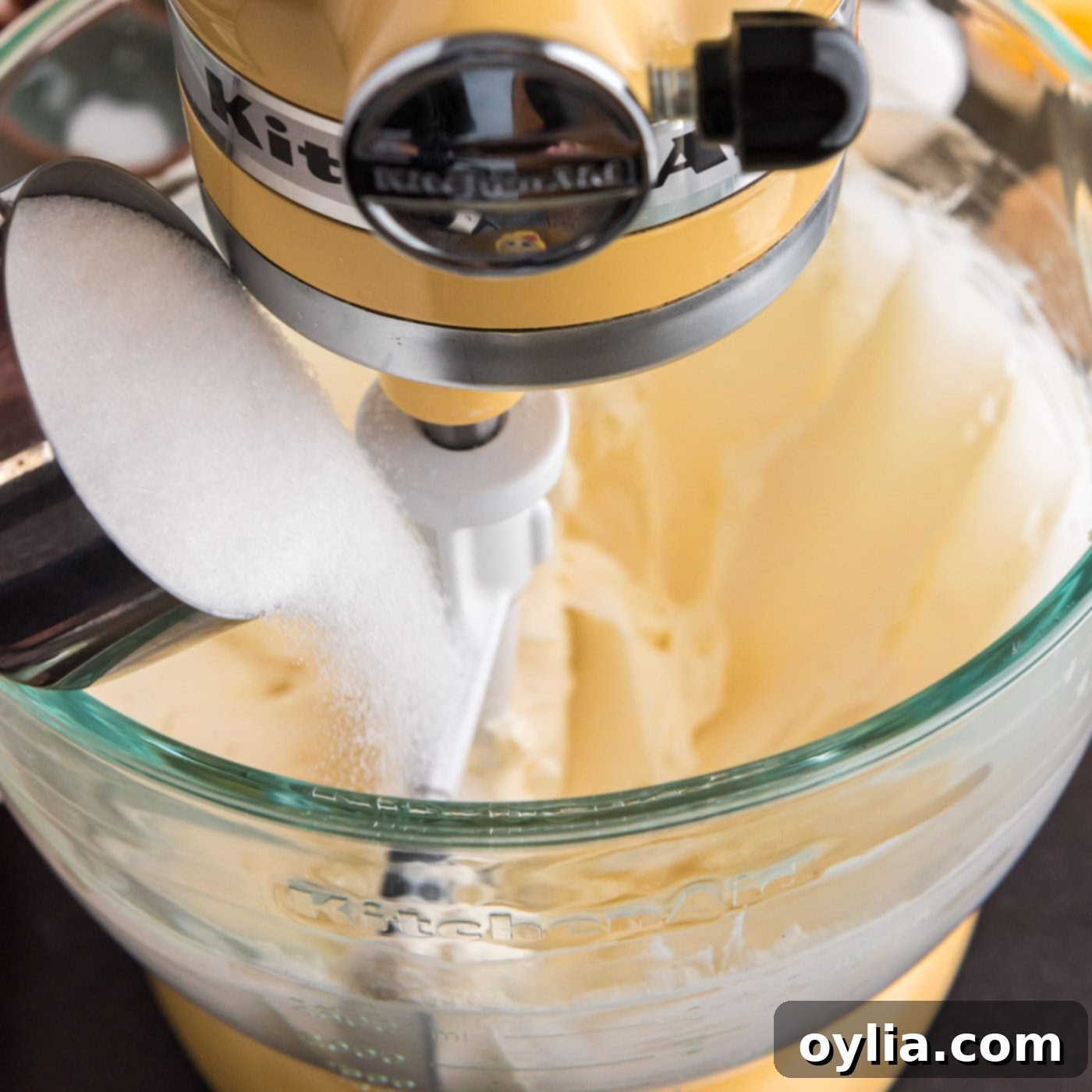 pouring sugar into bowl of whipped cream cheese