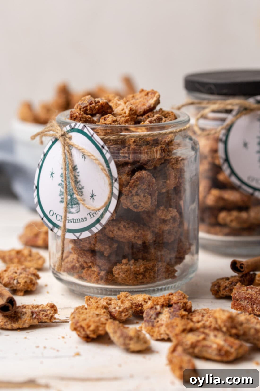 Close-up of perfectly coated cinnamon sugar candied pecans in a glass jar, tied with a festive ribbon.