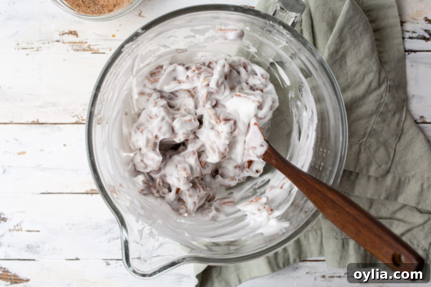 Tossing pecan halves in the egg white mixture with a spatula to coat evenly.