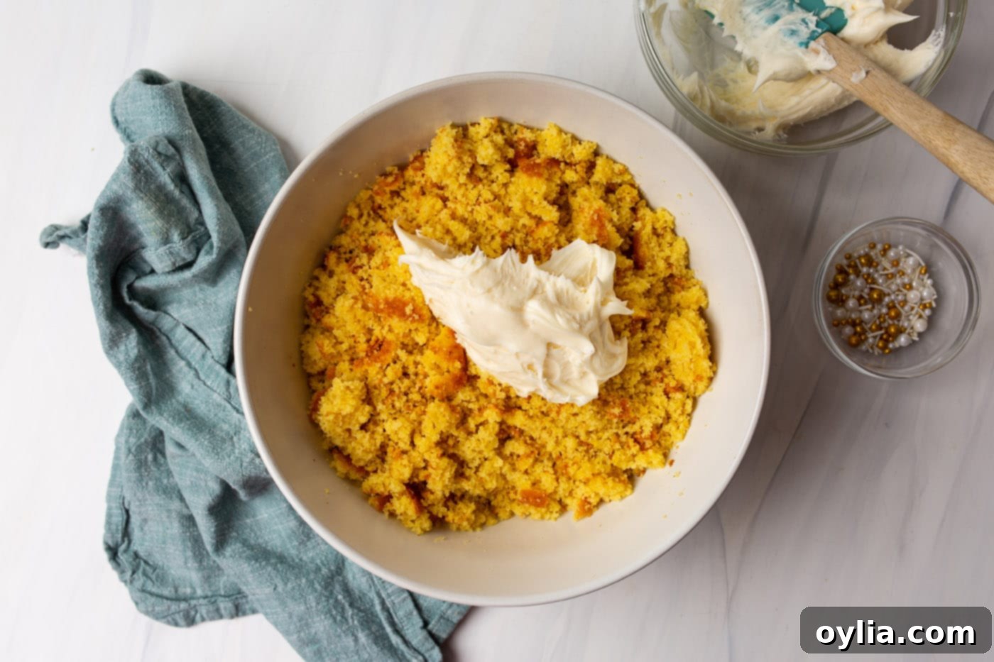 Crumbled cake in a bowl with vanilla frosting being mixed