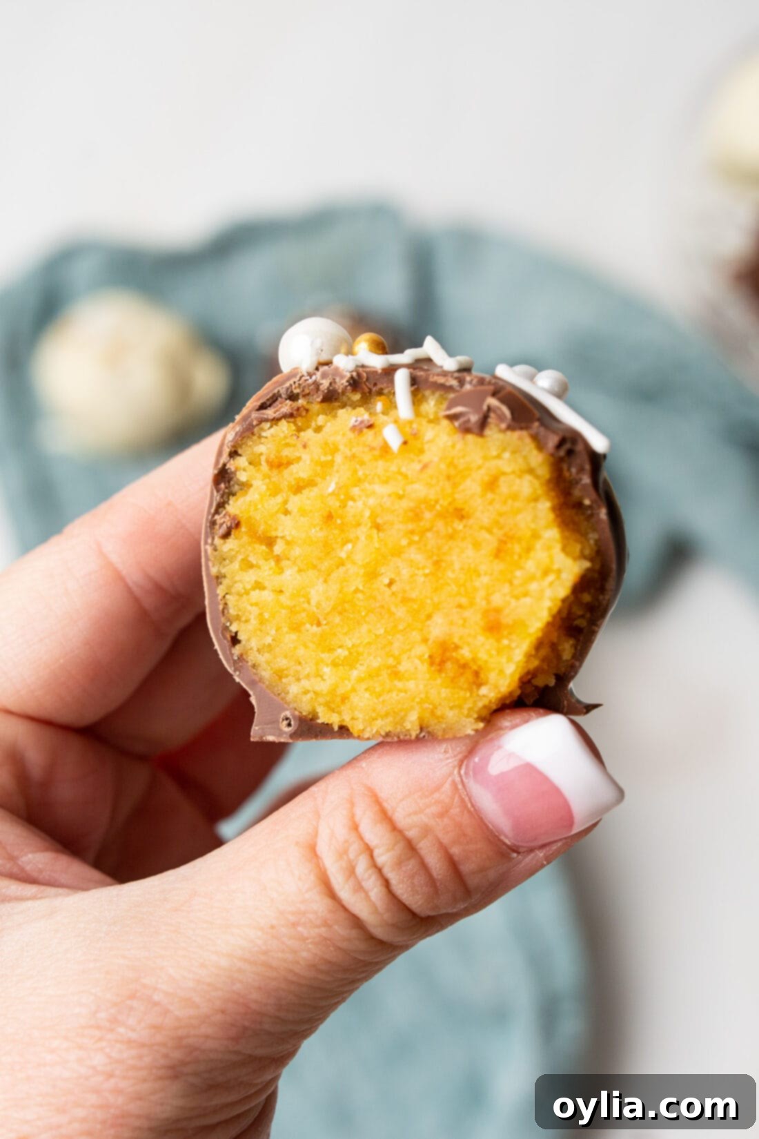 Decadent Cake Bites 10 Holding a halved cake ball, showing its moist interior