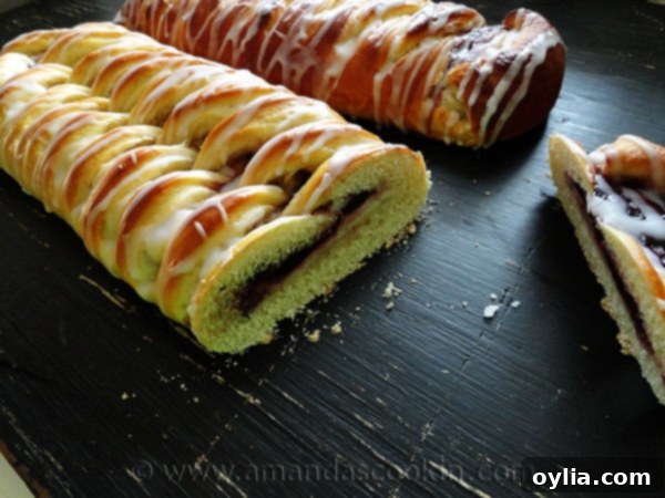 A close up photo of braided blackberry breakfast Danishes with a slice missing off of one.