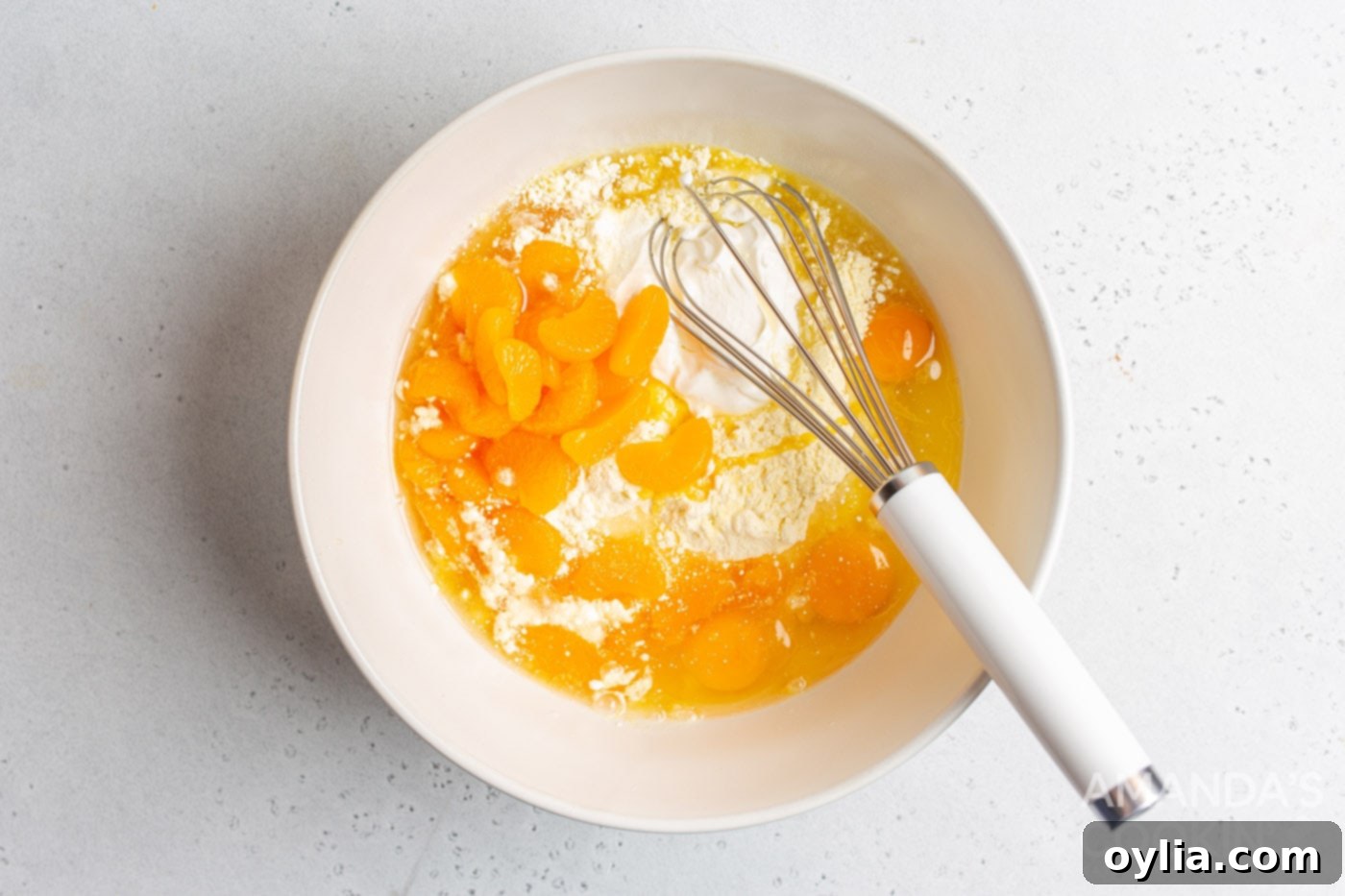 yellow cake mix, vegetable oil, sour cream, eggs, and mandarin oranges in a mixing bowl
