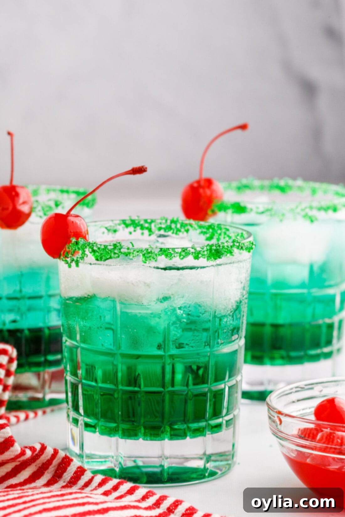 Festive Grinch Cocktail with green sugared rim and cherry
