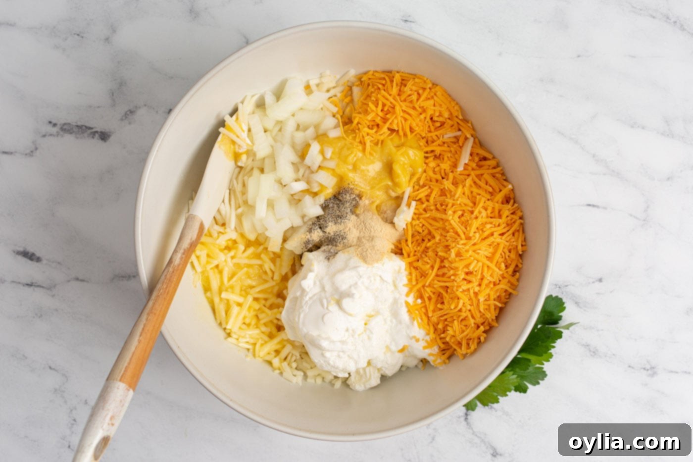 cheese, hashbrowns, sour cream, and cream of chicken soup with seasonings in a mixing bowl