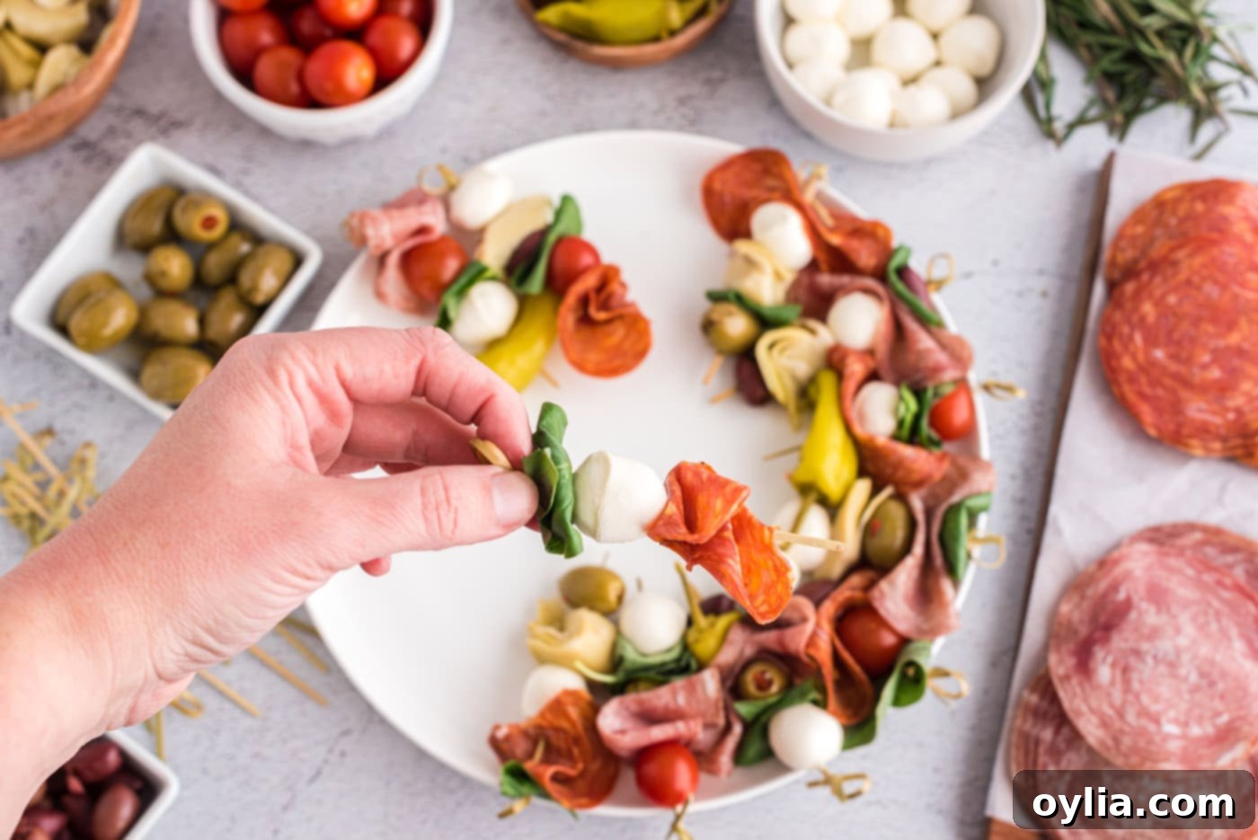 A skewer featuring a basil leaf, mozzarella ball, and folded prosciutto.