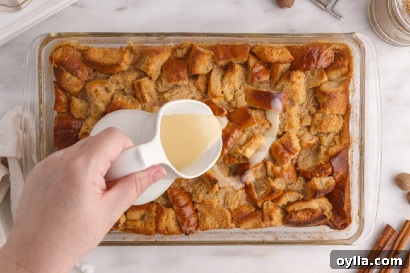 pouring vanilla sauce over bread pudding