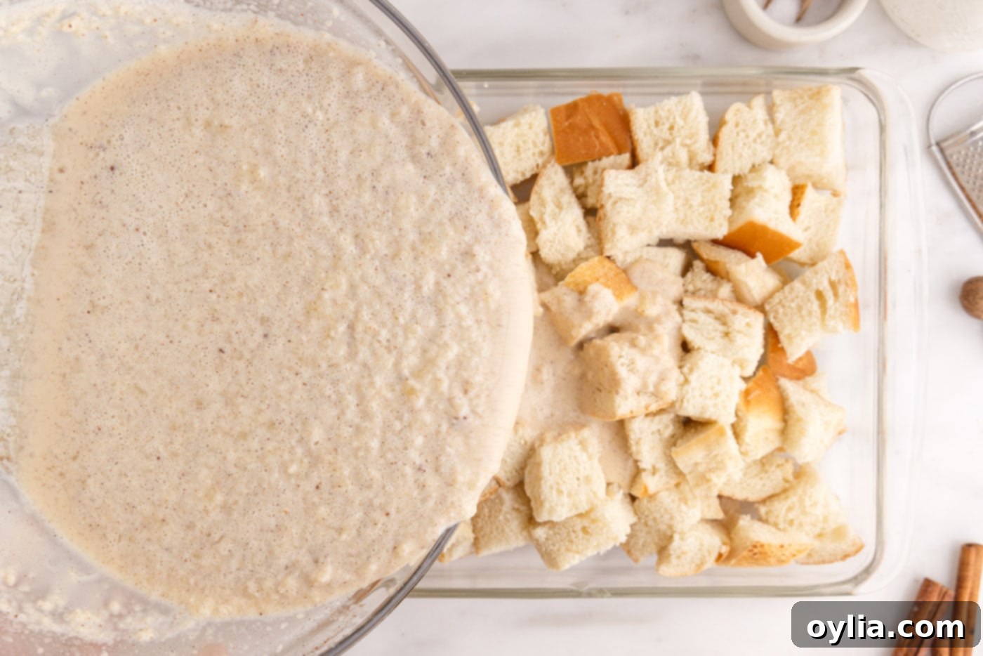 pouring cream mixture over bread cubes in a baking dish