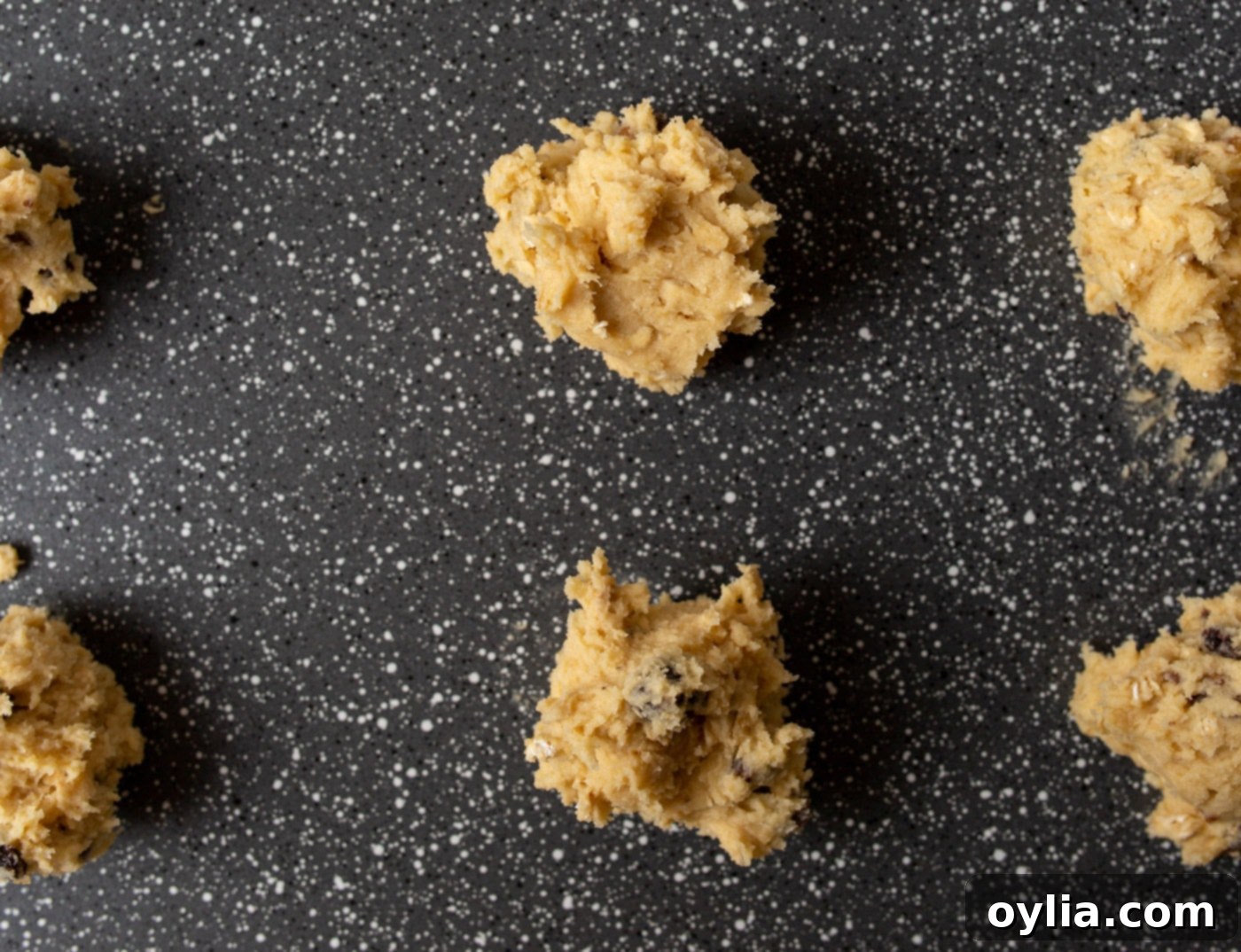 rows of oatmeal raisin cookie dough balls on a baking sheet