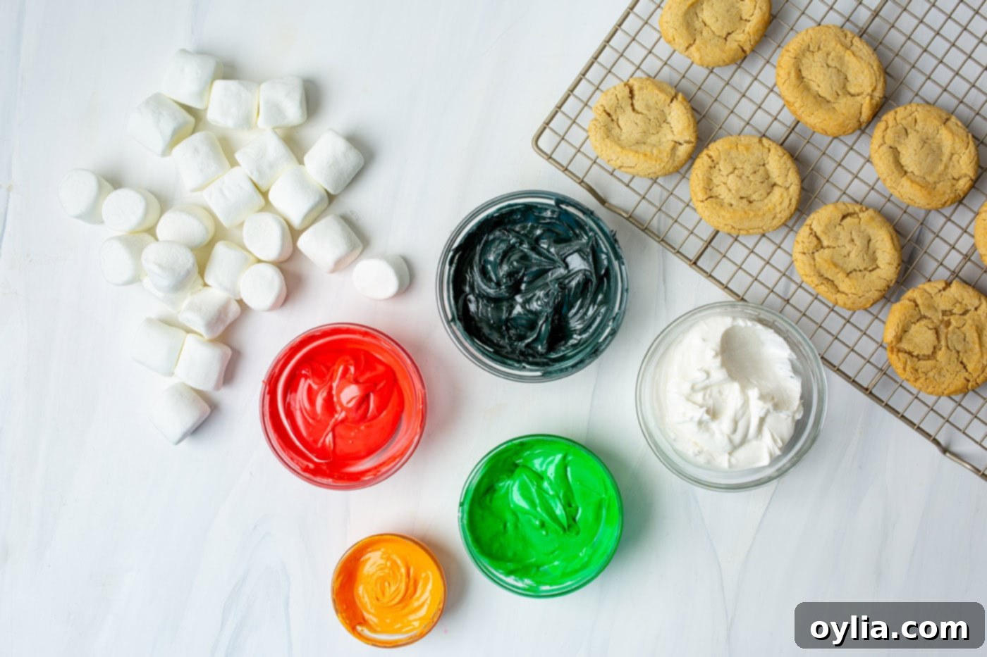 colorful icing in bowls with marshmallows and cookies