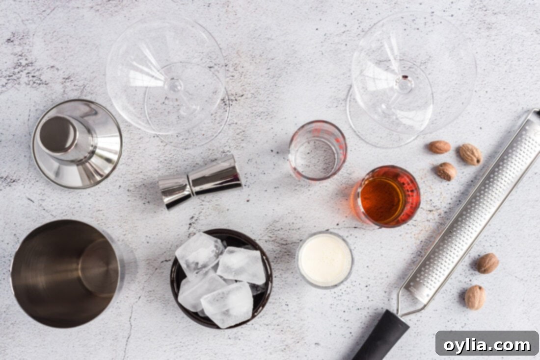 A flat lay of the ingredients for a Brandy Alexander cocktail: cognac, creme de cacao, heavy cream, and a whole nutmeg.