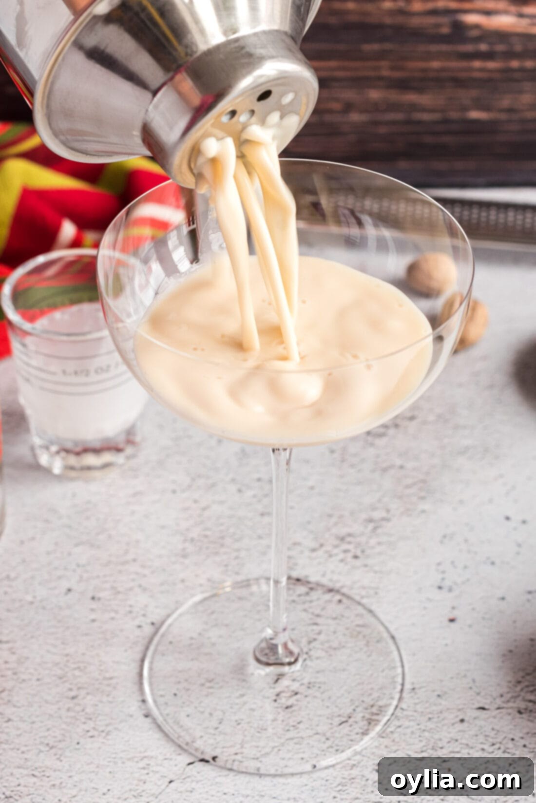 A bartender straining a freshly mixed Brandy Alexander into a martini glass, creating a perfectly smooth cocktail.