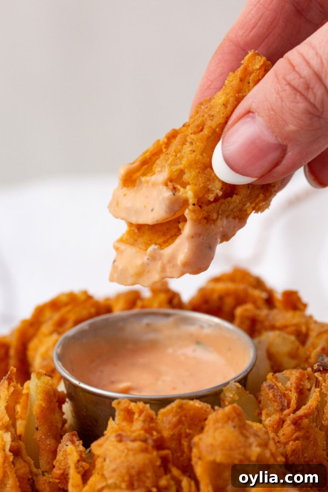 Crispy Onion Blossom 3 dipping a piece of Blooming Onion