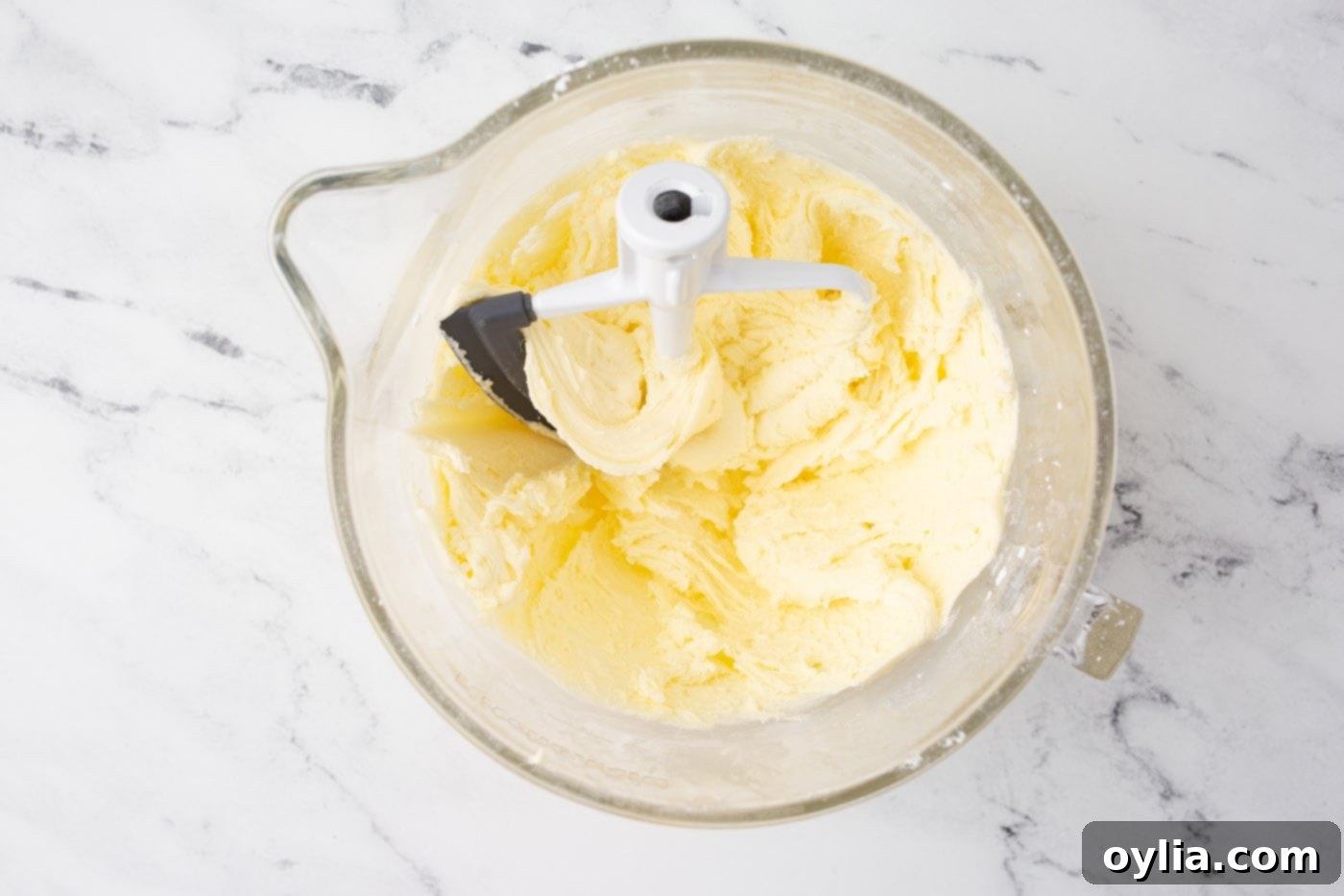 Smooth and fluffy lemon buttercream frosting in a stand mixer bowl, ready for cake decoration.
