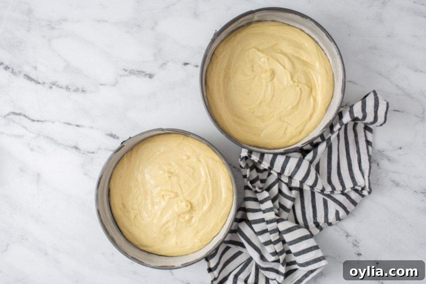 Lemon cake batter poured into two round cake pans, ready for baking.