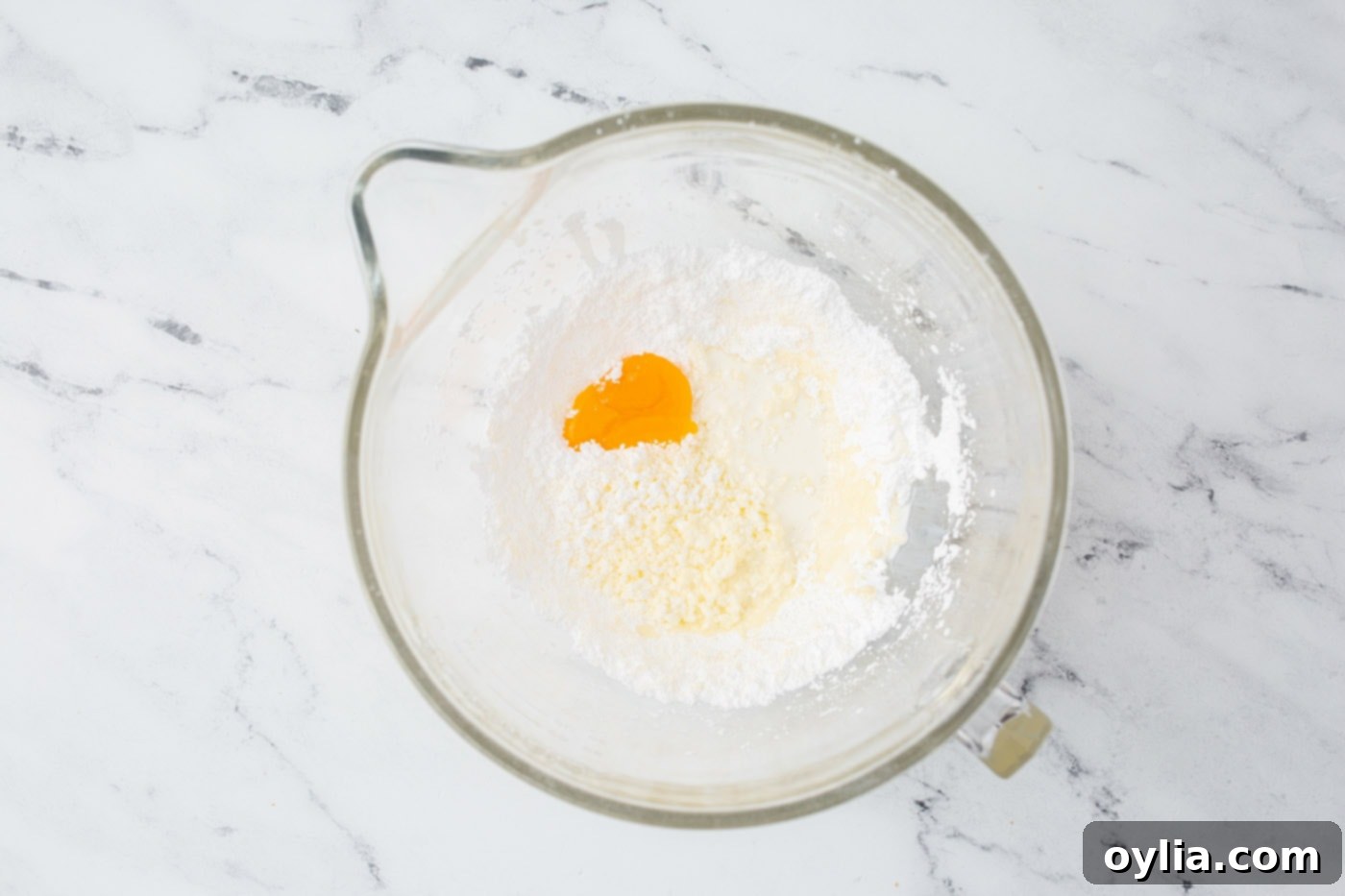 Butter and half of the powdered sugar being creamed in a stand mixer bowl for the lemon frosting.