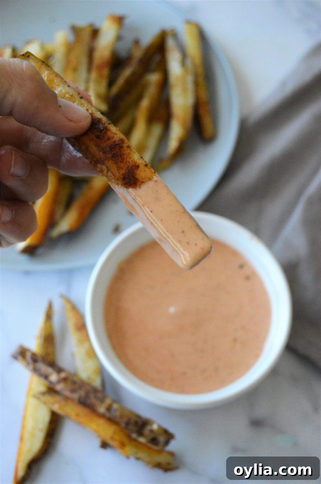 A crispy french fry being dipped into a bowl of homemade French Fry Sauce, showing its perfect consistency.