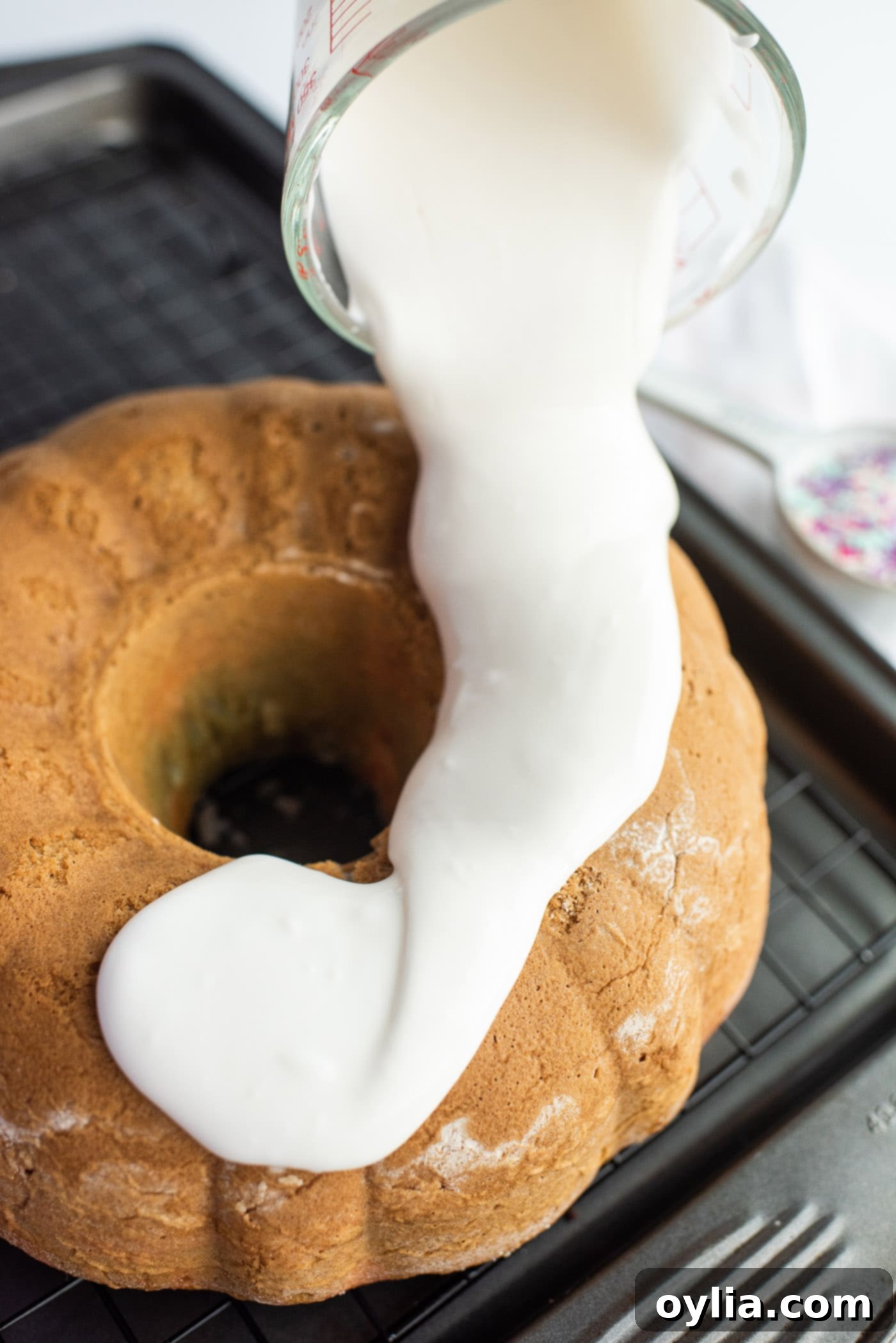 Pouring vanilla glaze over a completely cooled bundt cake.