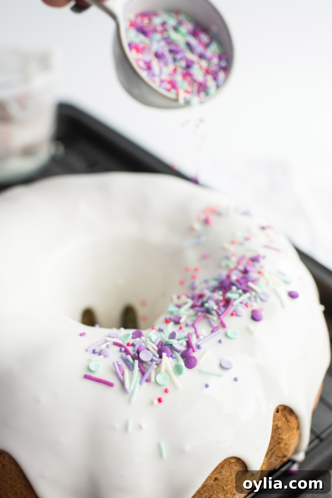 Adding colorful unicorn sprinkles to the freshly glazed bundt cake.