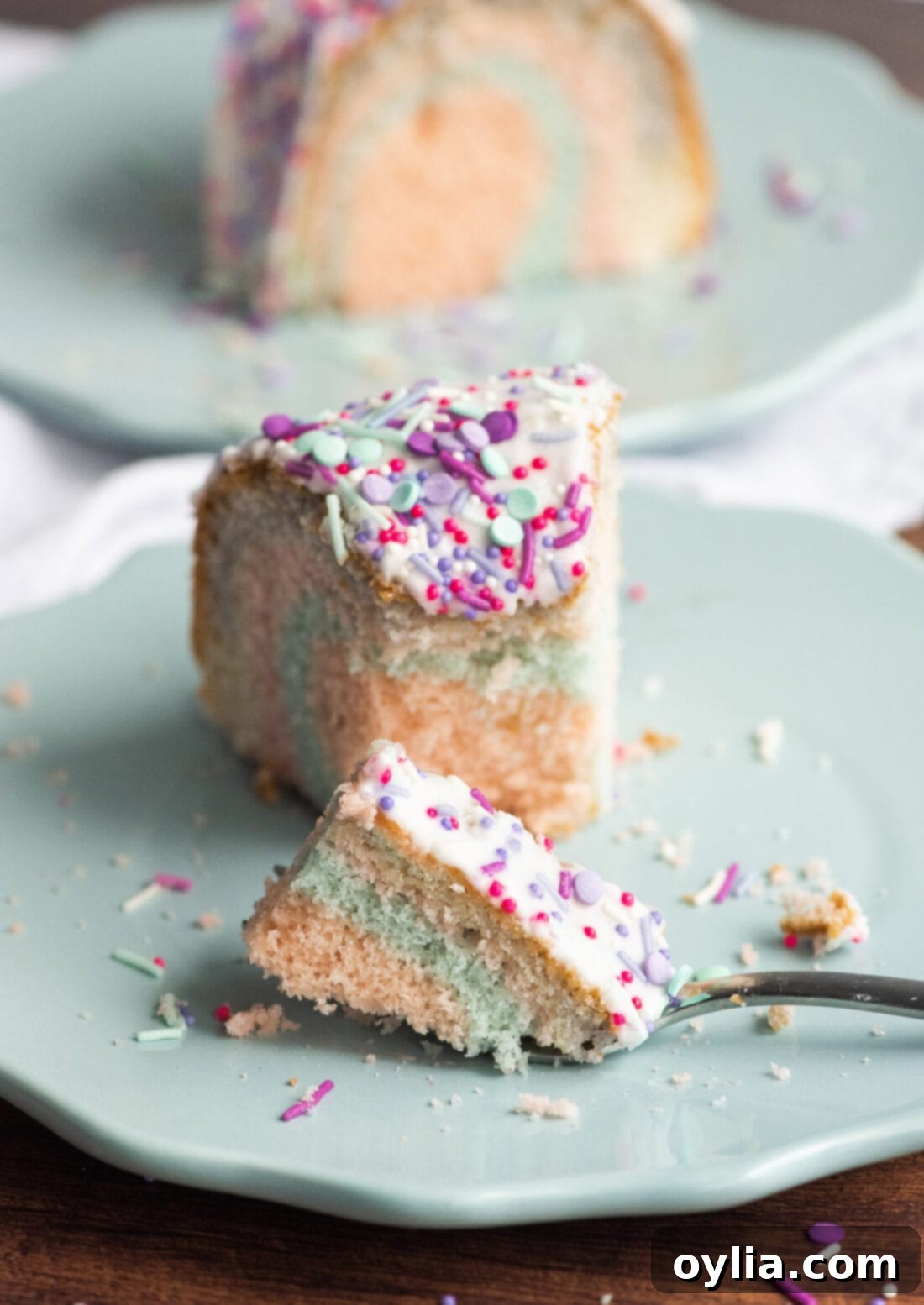 A perfectly cut slice of Unicorn Bundt Cake on a plate, showing the pastel rainbow interior.