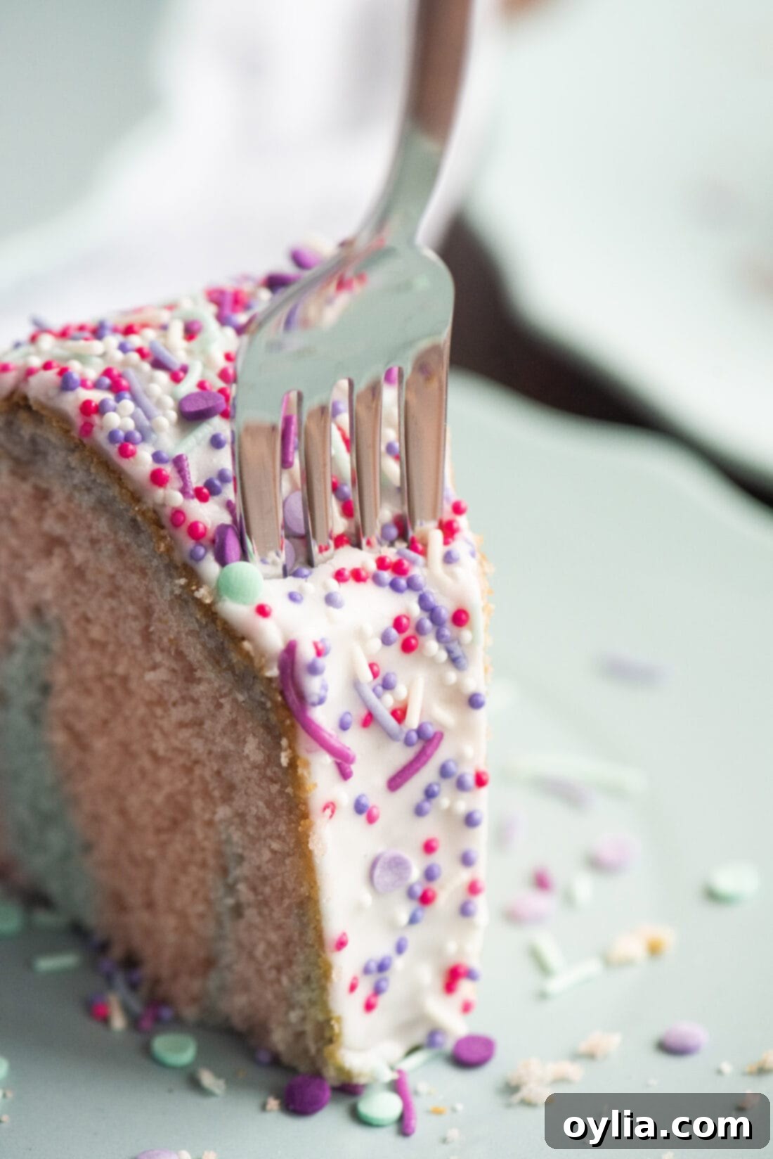 A slice of Unicorn Bundt Cake with a fork, showcasing the beautiful pastel rainbow layers.