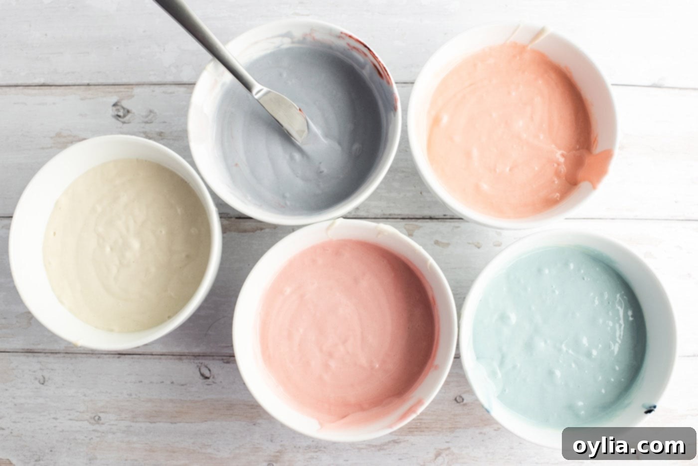 Bowls of cake batter colored with various pastel food colorings.