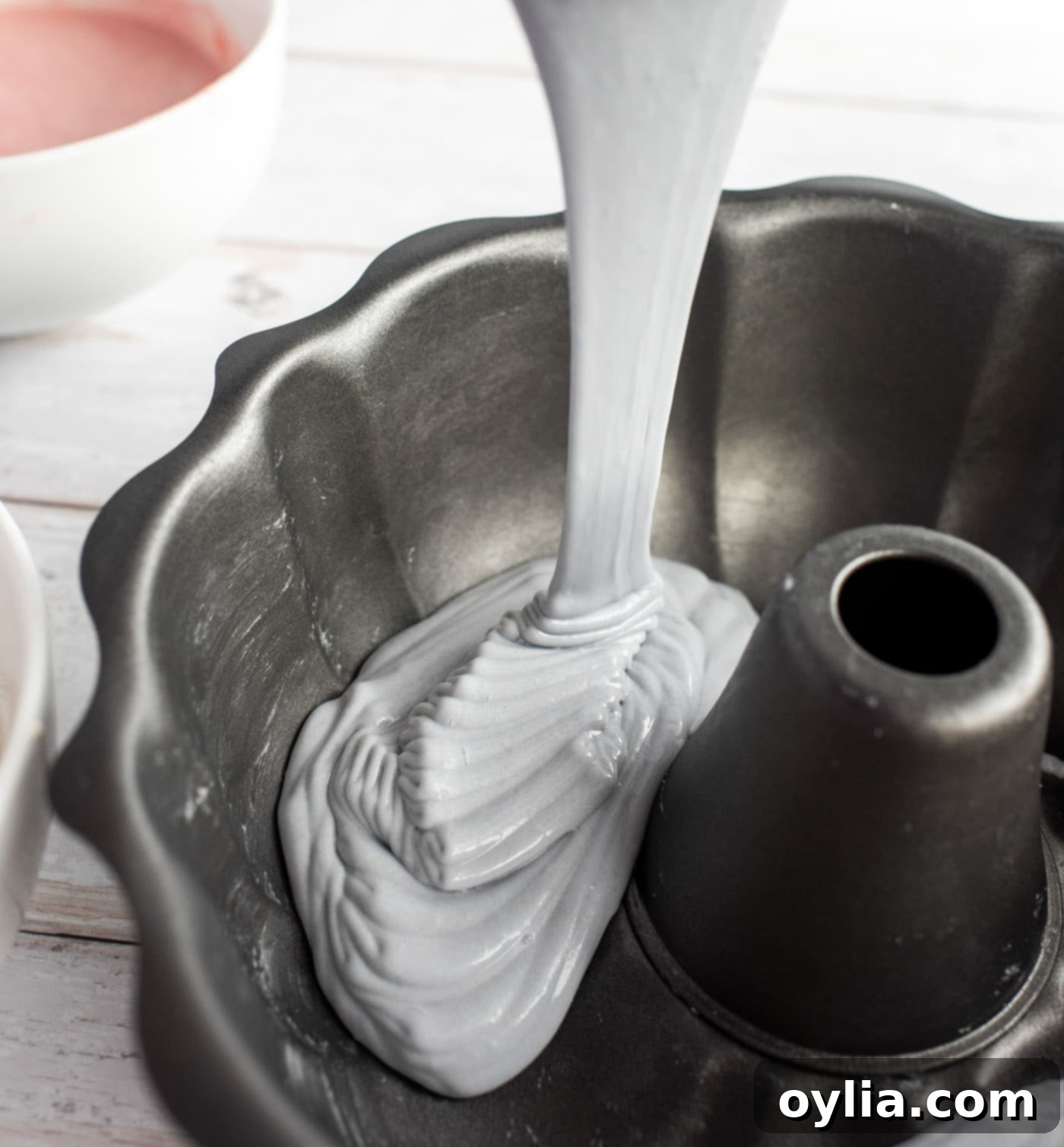 Pouring pastel purple cake batter into a bundt pan.