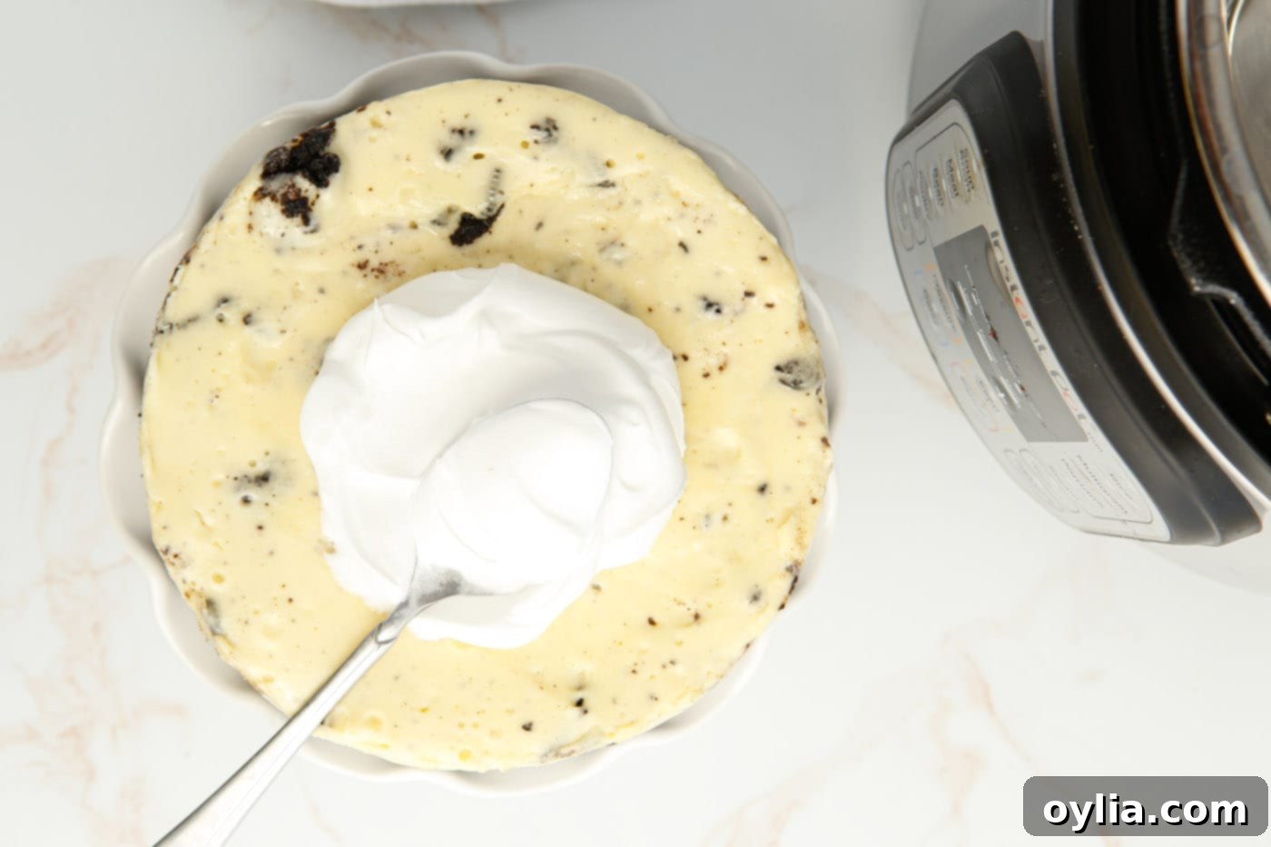 Spreading smooth whipped cream over the top of a chilled Instant Pot Oreo Cheesecake