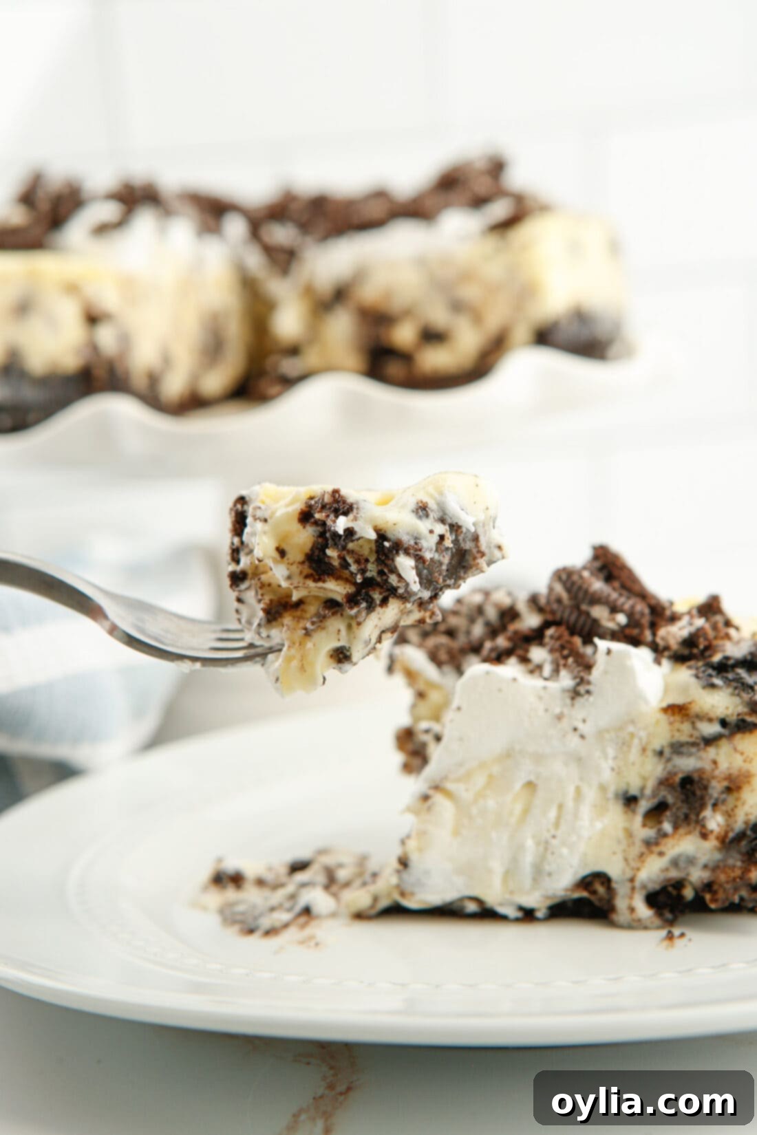 Close-up of a fork holding a bite of Instant Pot Oreo Cheesecake, highlighting the rich, creamy texture and cookie bits