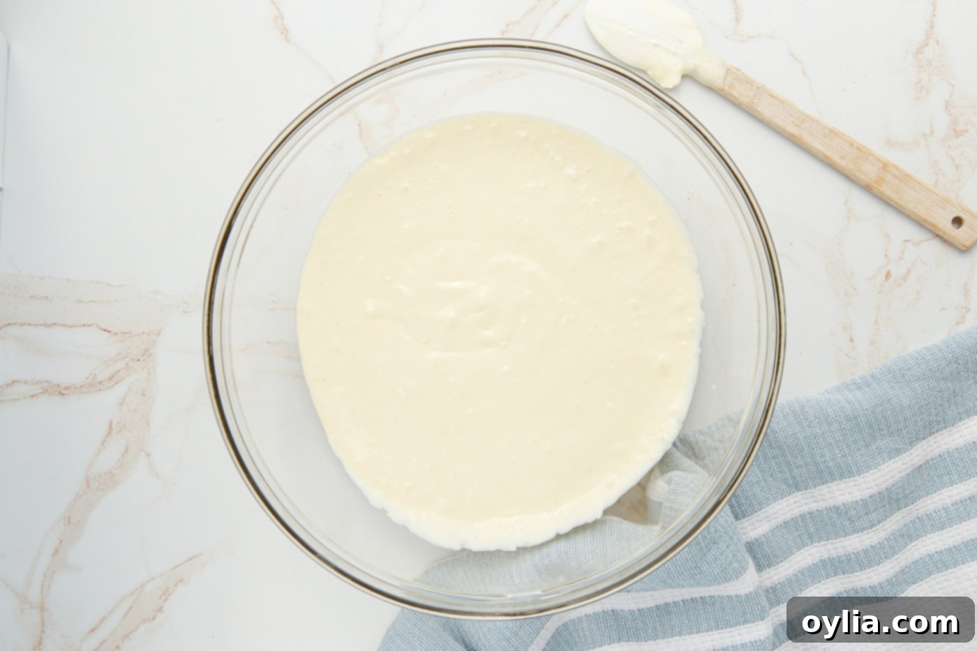 Creamy cheesecake mixture in a large mixing bowl being beaten to a smooth consistency