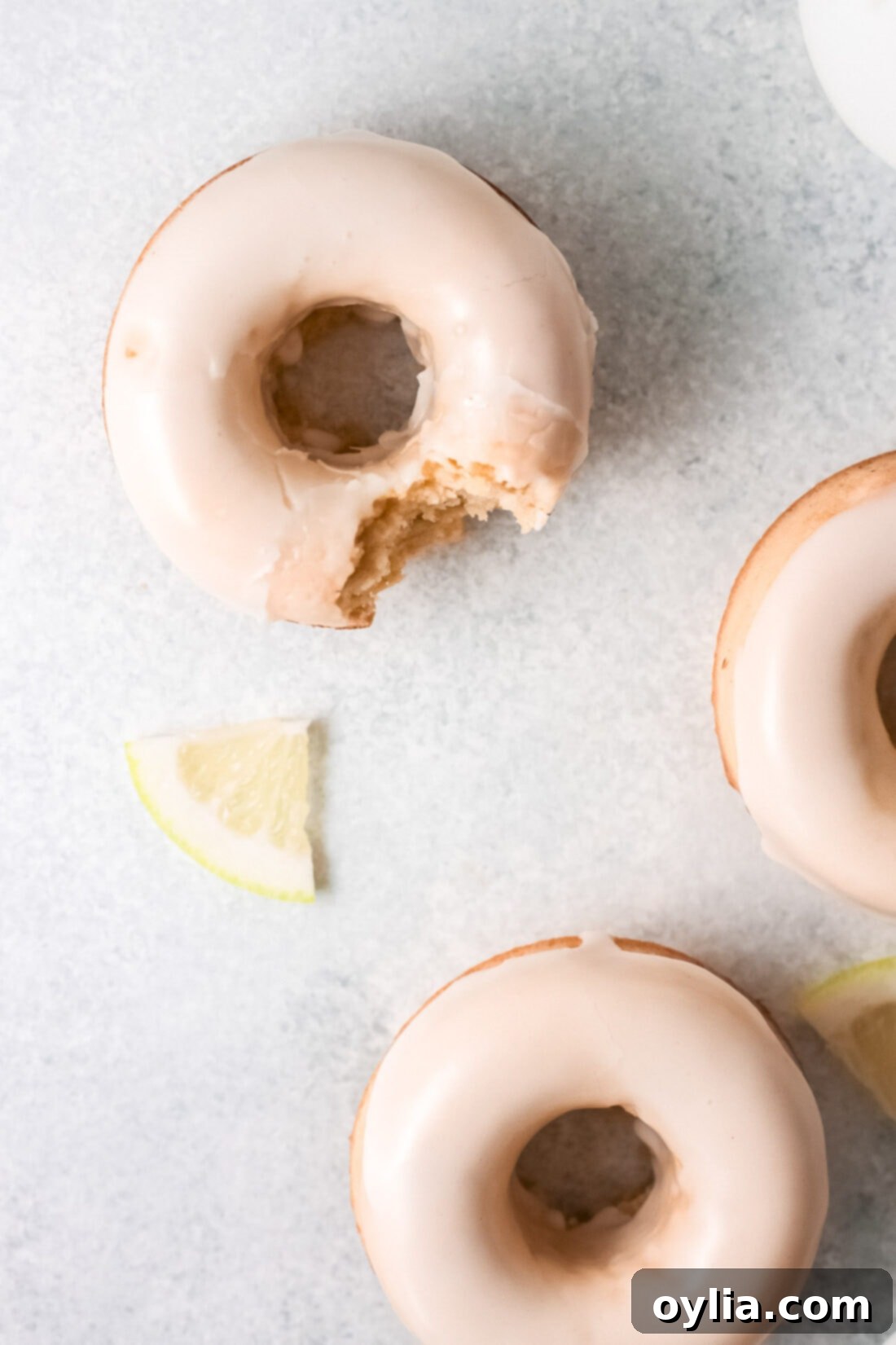 A lemon baked donut with a bite taken out, showing the soft interior