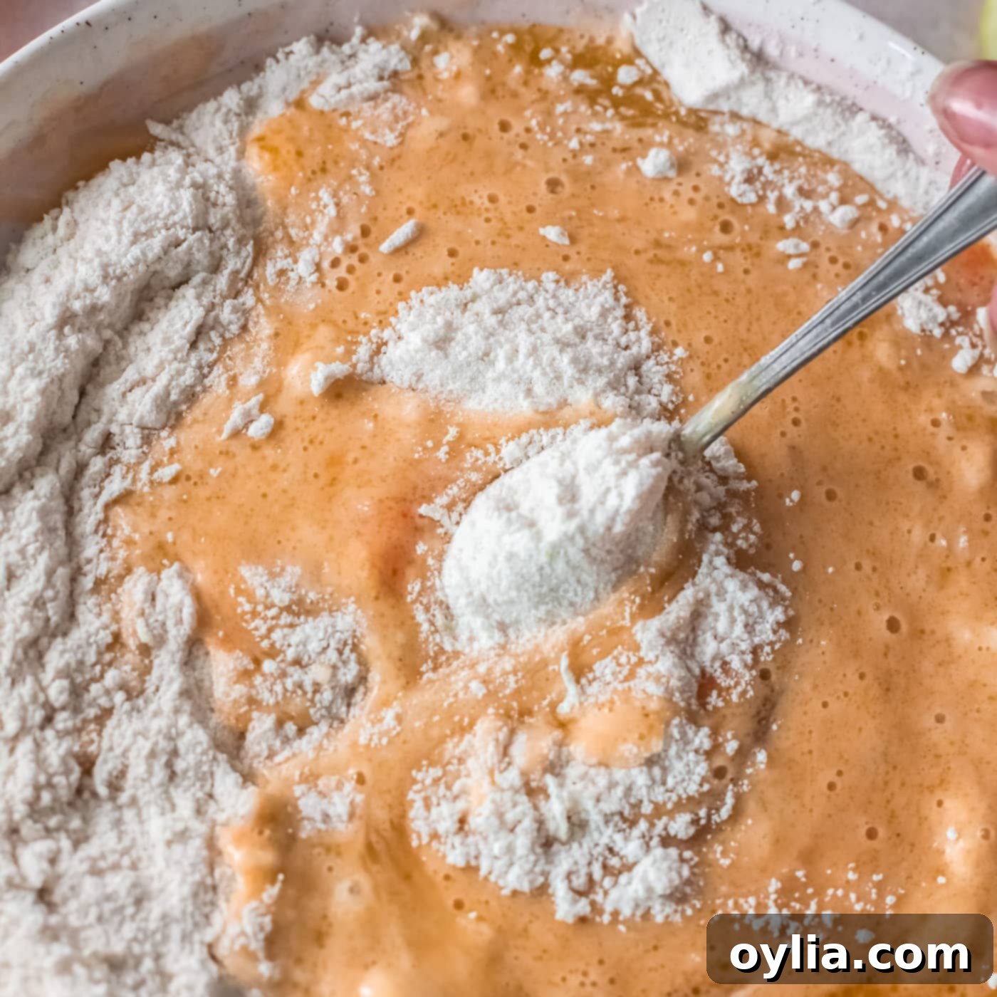 mixing wet ingredients into dry ingredients for donuts, showing a partially mixed batter